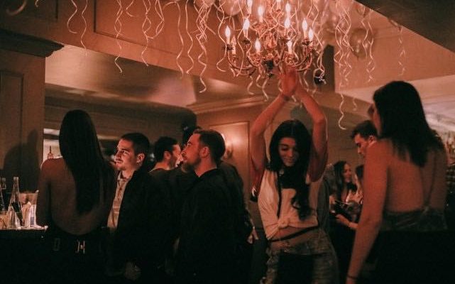 Young woman dances under the chandelier with lots of balloons at Mayfair cocktail bar